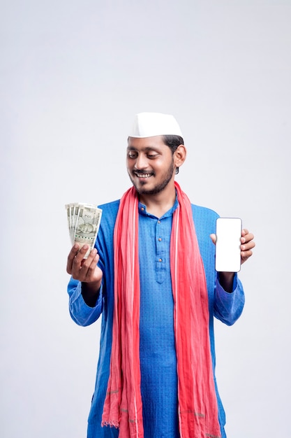 Young indian farmer showing smartphone and money on white background.