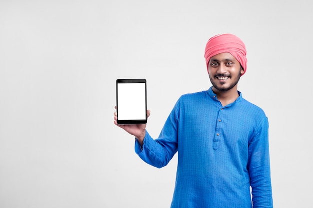 Young indian farmer showing tablet and giving expression on white background.