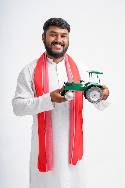 Young indian farmer showing tractor toy on white background