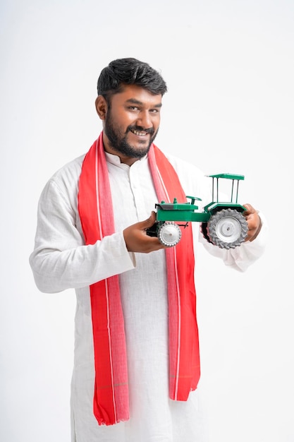 Young indian farmer showing tractor toy on white background