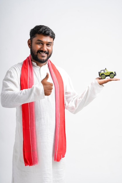 흰색 바탕에 차량 장난감을 보여주는 젊은 인도 농부