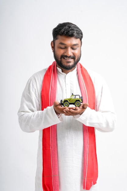 Young indian farmer showing vehicle toy on white background