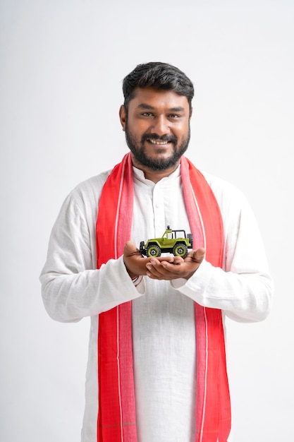 Young indian farmer showing vehicle toy on white background