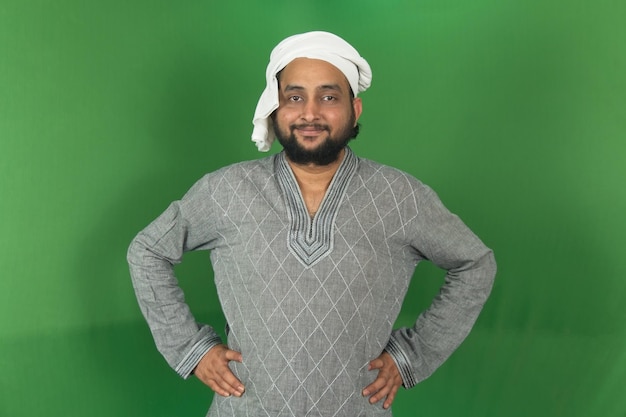 young indian farmer smiling and looking at camera hands on waist isolated on green background green