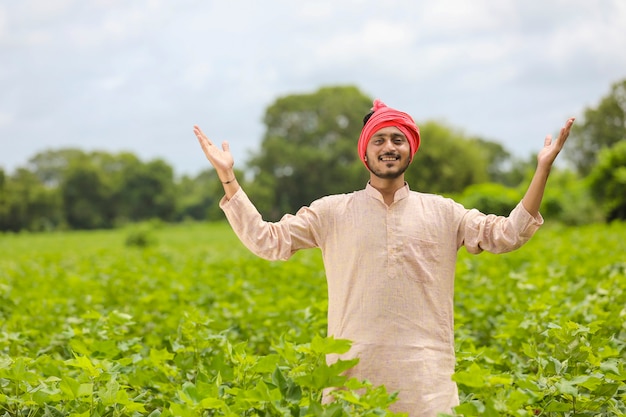 Young indian farmer standing at agriculture field.