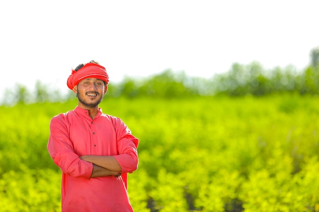 Young indian farmer standing in green pigeon pea field