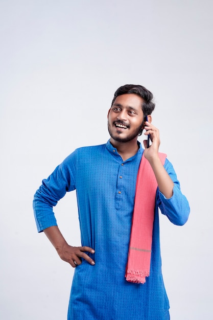 Young indian farmer talking on mobile phone over white background.