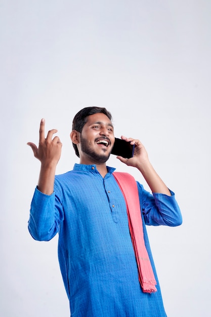 Young indian farmer talking on mobile phone over white background.