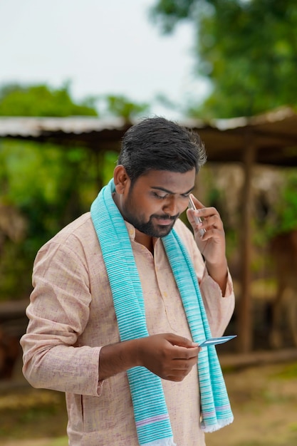 Young indian farmer talking on smartphone.