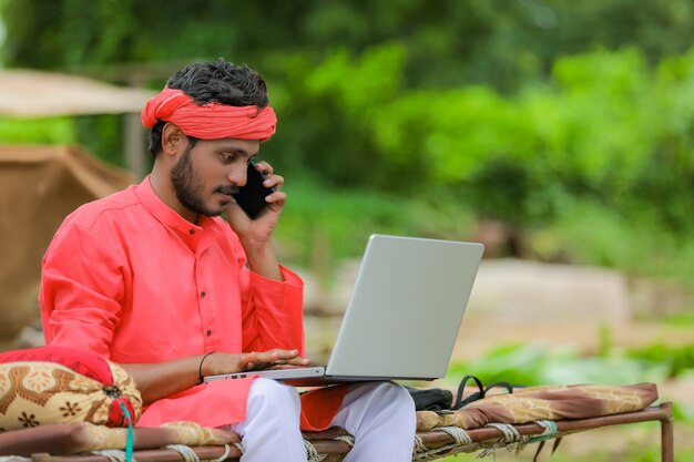 Young indian farmer using a laptop