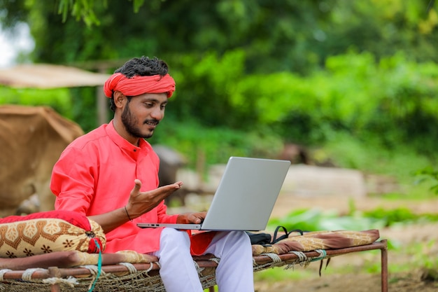 Young indian farmer using the laptop