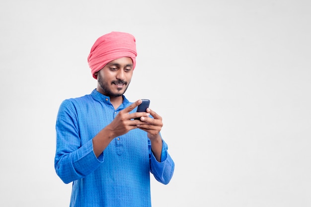 Young indian farmer using mobile phone over white background.