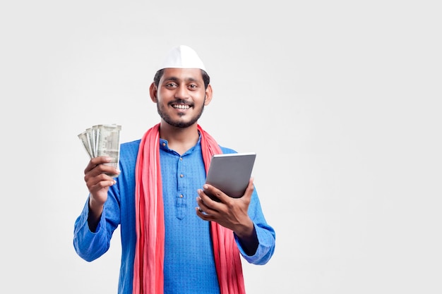 Молодой индийский фермер с помощью смартфона и показывает деньги на белом фоне.