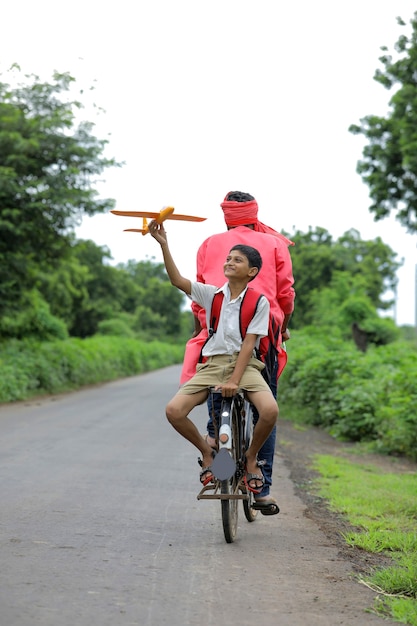 Young indian farmer with his son on a bike