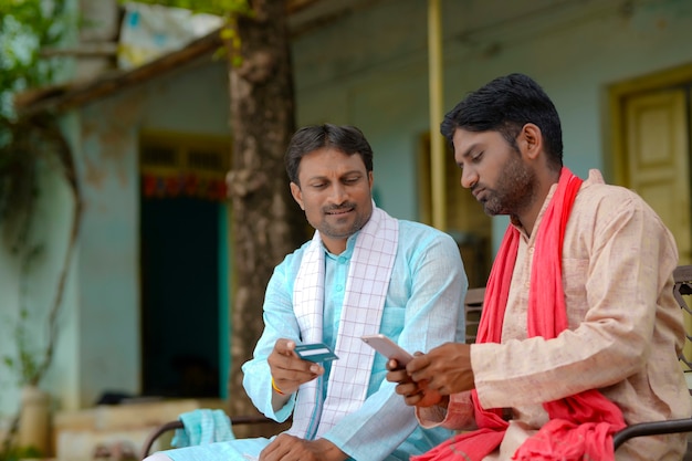 Young indian farmers using debit or credit card with smartphone at home