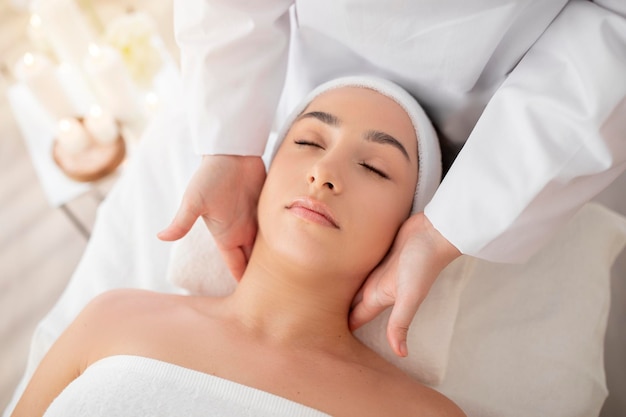 Photo young indian female enjoying therapeutic neck massage in spa