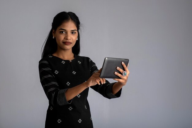 Young Indian girl using a mobile phone or smartphone on gray