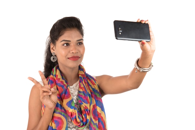 휴대 전화 또는 스마트 폰을 사용하는 젊은 인도 소녀는 공백에 고립