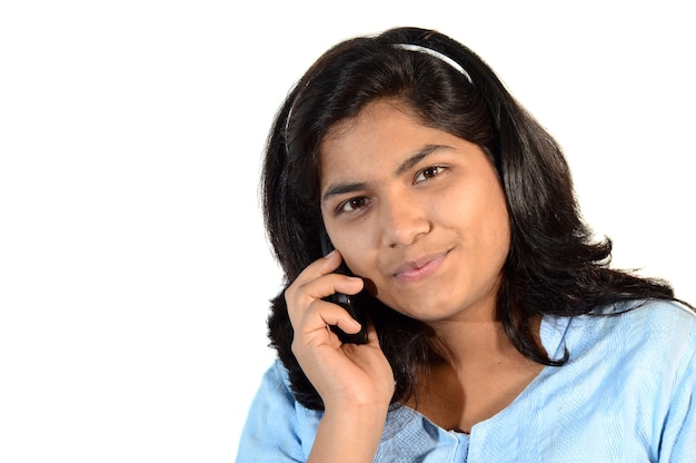 屋外の公園で携帯電話やスマートフォンを使用して若いインドの女の子
