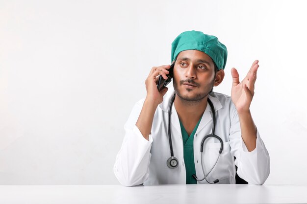 Young indian male doctor talking on smartphone at clinic.