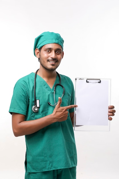 白い背景の上にメモ帳を表示聴診器と制服を着た若いインドの男性医師。
