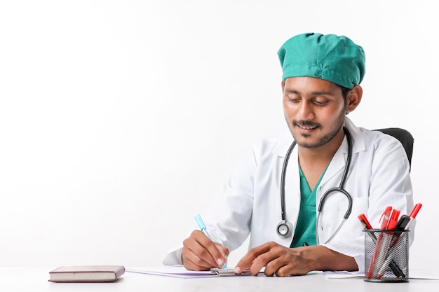 Фото Молодой индийский мужской доктор писать на блокноте в клинике.