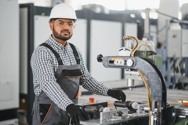 Young Indian male engineer wearing safety workwear standing in the factory