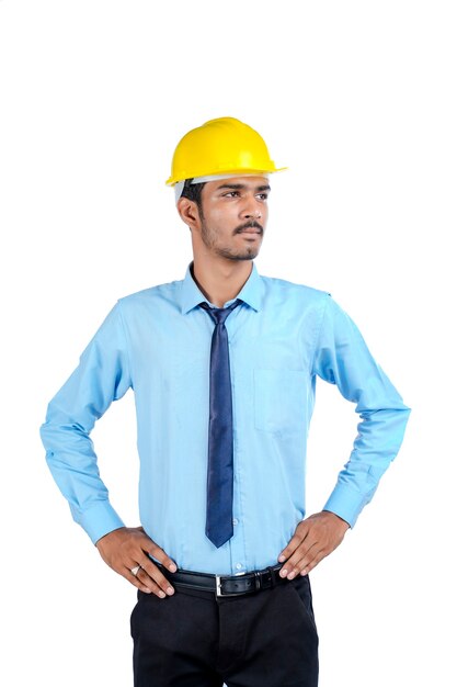 Young Indian male engineer wearing yellow color hard hat on white background.