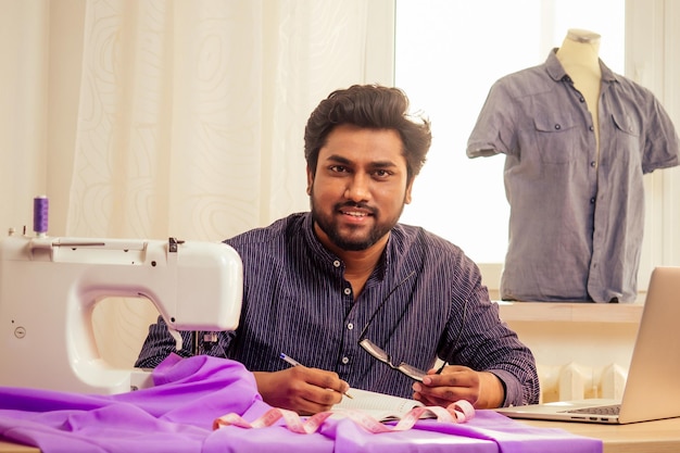 young indian male tailor working at home