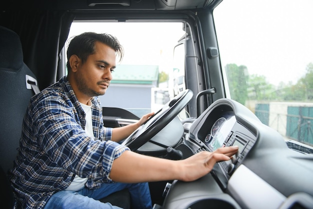 若いインド人の男性トラック運転手が車輪の後ろに座っている