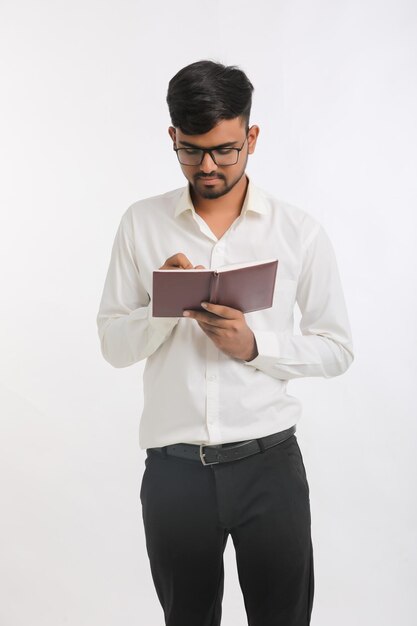 Young Indian male writing some detail in dairy over white background.