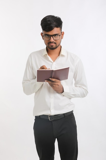 Young Indian male writing some detail in dairy over white background.