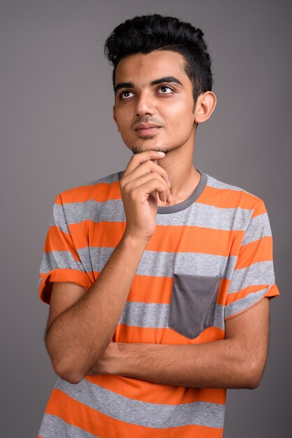 Young Indian man against gray wall