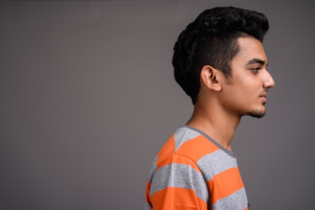 Young Indian man against gray wall