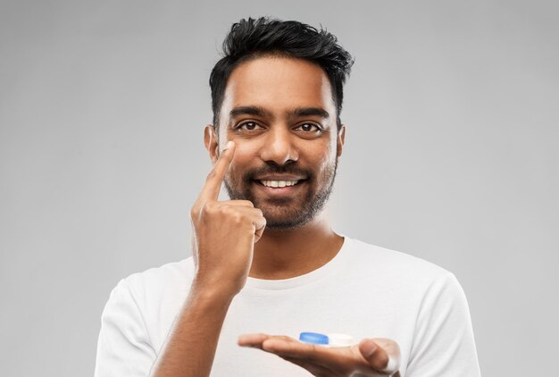 young indian man applying contact lenses