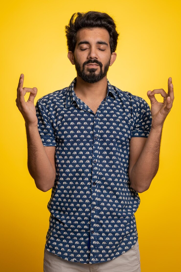 फोटो young indian man breathes deeply eyes closed meditating with concentrated thoughts peaceful mind