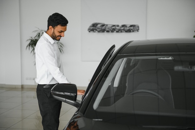 A young Indian man chooses a new car at a car dealership