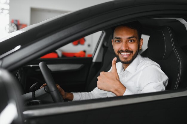 A young Indian man chooses a new car at a car dealership