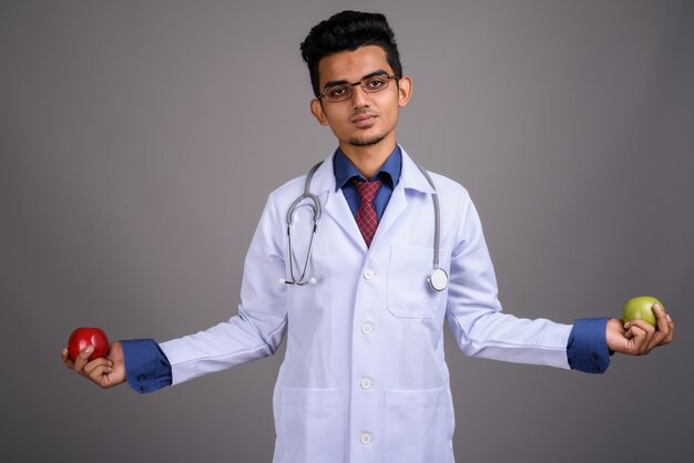 Young Indian man doctor on gray wall