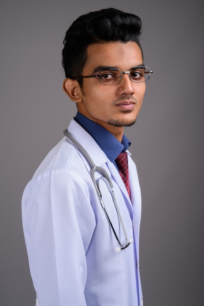 Young Indian man doctor on gray wall