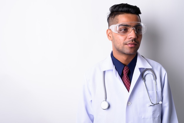 Young Indian man doctor wearing protective eyeglasses on white