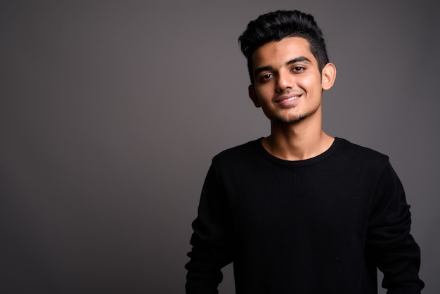 Young Indian man on gray wall