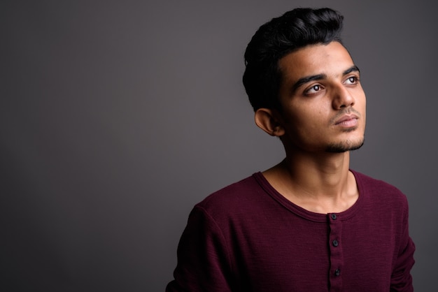 Young Indian man on gray wall