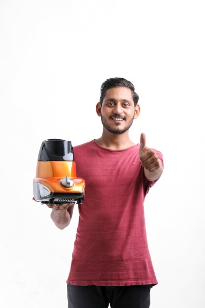 Young indian man holding electronic mixer in hand over white background.