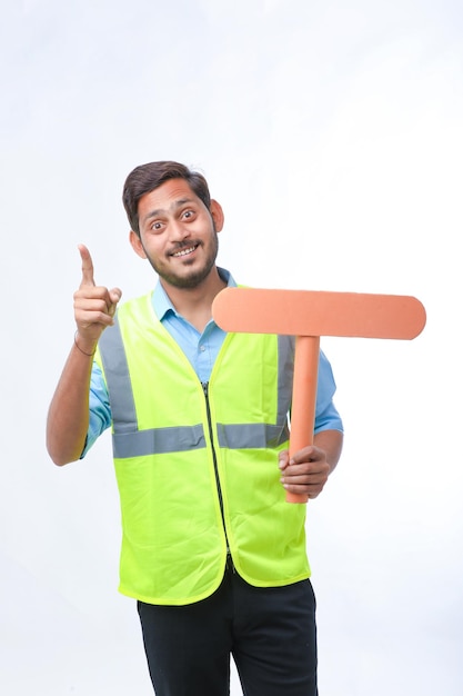 Young indian man holding a empty sign board on white background. construction work concept