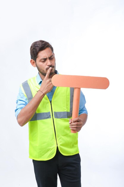 Young indian man holding a empty sign board on white background. construction work concept