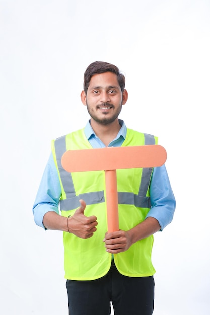 Young indian man holding a empty sign board on white background. construction work concept