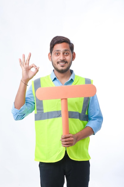 Young indian man holding a empty sign board on white background. construction work concept