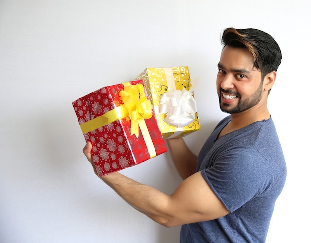 Молодой индийский мужчина держит подарочную коробку, рождество, день святого валентина, день рождения, концепцию счастья