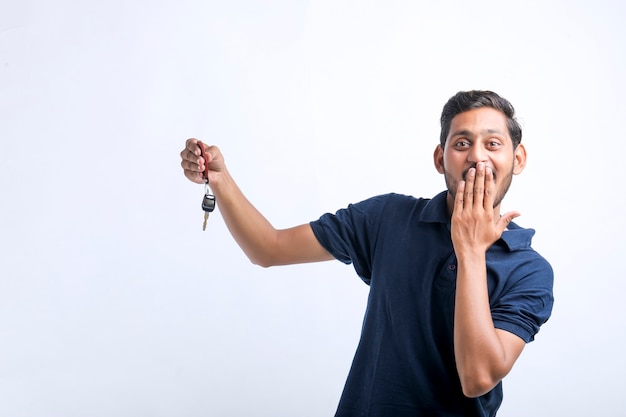 Young indian man holding key in hand over white background.